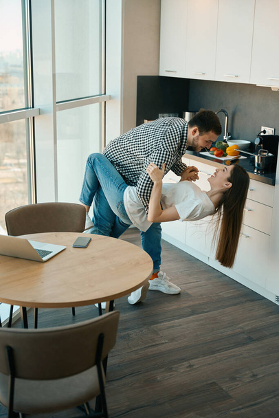 Cheerful beautiful young couple dancing tango in the kitchen, guys in comfortable home clothes - Fotoğraf, Görsel