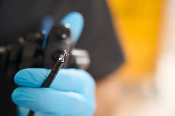 Primer plano de la mano del médico en el guante de nitrilo que sostiene la sonda endoscópica con pinzas de biopsia - Foto, Imagen
