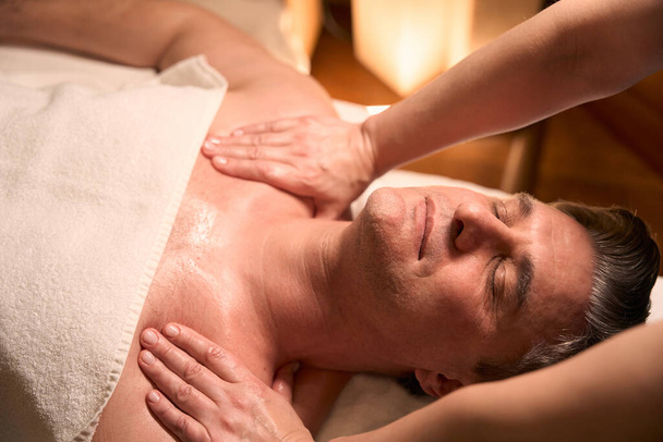 Обрізана фотографія кваліфікованого масажиста, що натискає на пускові точки з обох сторін клієнтської шиї
 - Фото, зображення