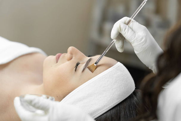 De foto toont de magie van cosmetische peeling, waarbij elke fase van de procedure helpt de huid van de jonge vrouwen gezicht te herstellen en te vernieuwen. Een mooie patiënt in een schoonheidskliniek is ontspannen en - Foto, afbeelding