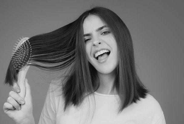Close up portrait of happy beautiful girl with shiny hair with comb. Attractive smiling woman brushing hair - Фото, зображення