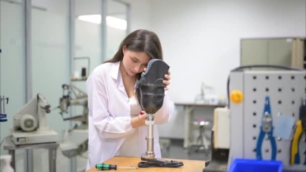義肢の検査と研究室で働く若い女性技術者、義肢製造のハイテク技術を持つ専門家、障害者のための新しい人工肢生産 - 映像、動画