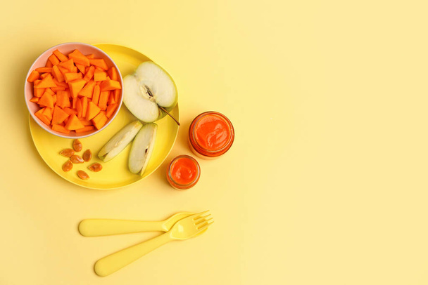 Баночки здорового дитячого харчування, свіжий гарбуз та яблуко на кольоровому фоні
 - Фото, зображення