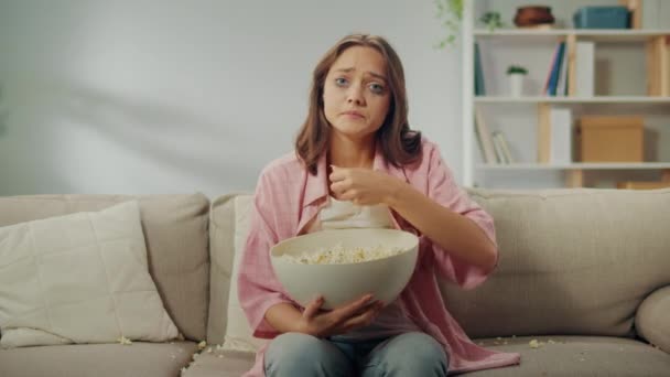 Nuori nainen istuu sohvalla, syö popcornia ja katsoo surullista elokuvaa. Nainen itkee katsoessaan melodraamaa. Elokuvat keinona emotionaalinen outlet ja itseilmaisun. Elokuva ja sen rooli. - Materiaali, video