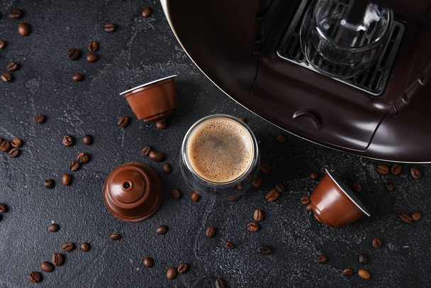 Copo de café expresso delicioso, cafeteira cápsula, vagens e feijões na mesa grunge preto - Foto, Imagem
