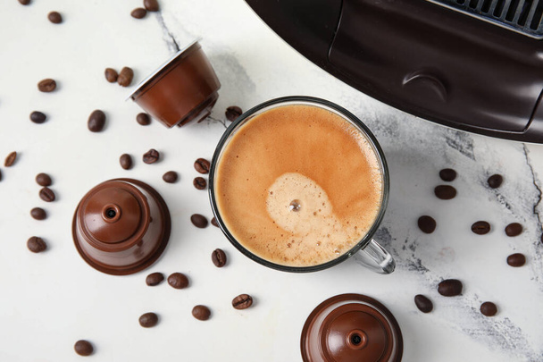Taça de café expresso delicioso, cafeteira cápsula, vagens e feijões na mesa branca - Foto, Imagem