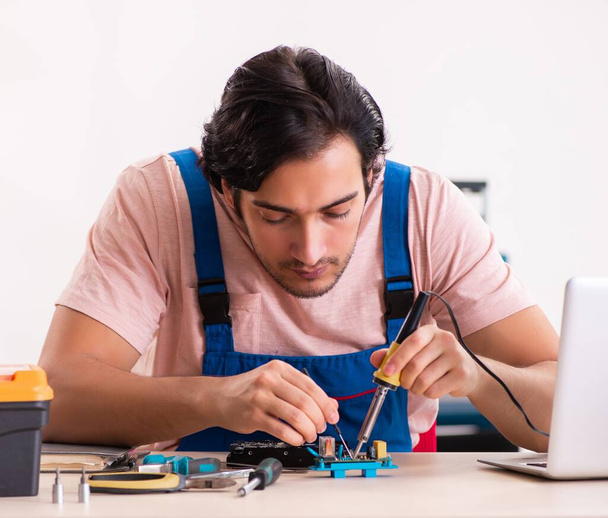 The young male contractor repairing computer - Foto, imagen