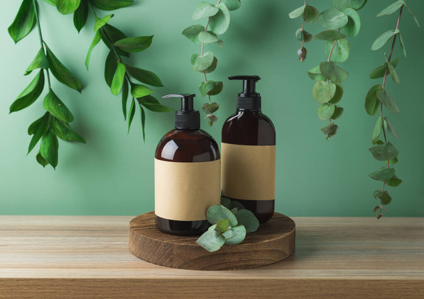 Natural cosmetics bottles with labels on wooden podium  for mock up packaging design over green leaves background - Foto, imagen