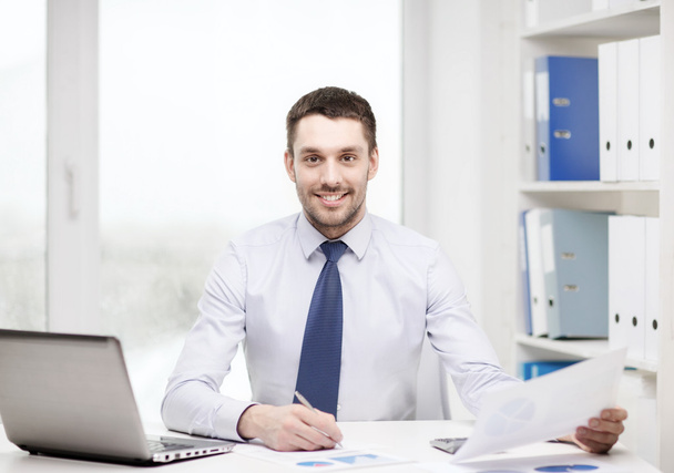 smiling businessman with laptop and documents - Fotó, kép