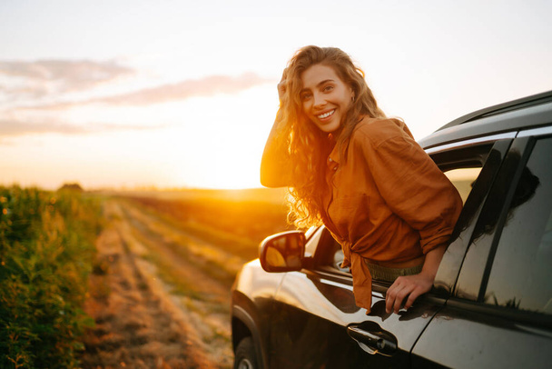 Car and summer with a female tourist taking a scenic drive at sunset. Lifestyle, travel, tourism, nature, active life. - Foto, afbeelding