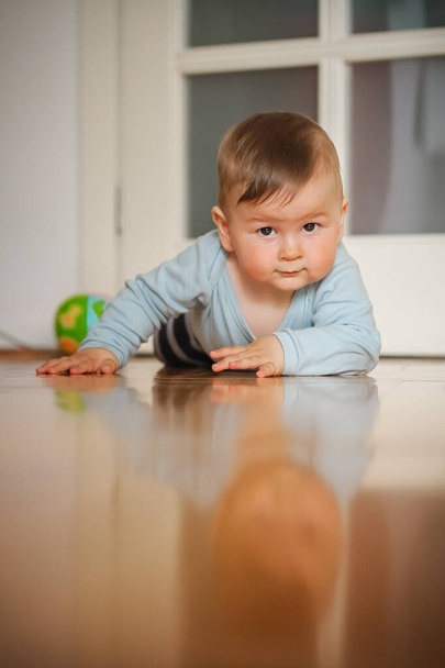 Cute baby boy crawls on the home floor, explore the world and learn to move. Love and family emotion - Photo, Image