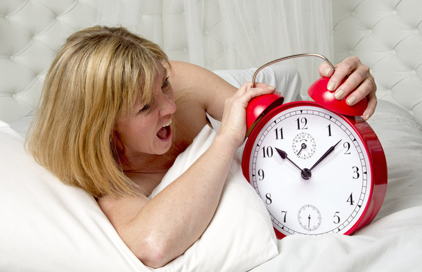 Woman with an alarm clock at wake up time - Photo, Image