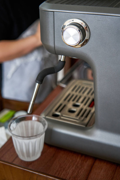 Un barista está haciendo un café con leche con una cafetera espresso - Foto, Imagen