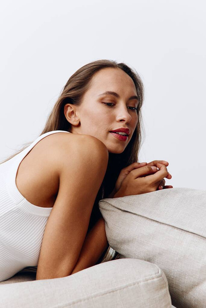 Красива жінка модель позує лежачи на подушках на підлозі з засмаглою шкірою, що доглядає за її тілом, косметичними процедурами вдома. Високоякісна фотографія - Фото, зображення