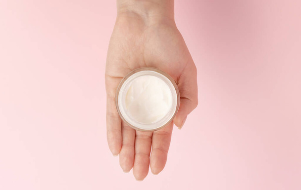 A jar with cream in a womans hand. View from above. Layout for advertising a cosmetic brand - Foto, Bild