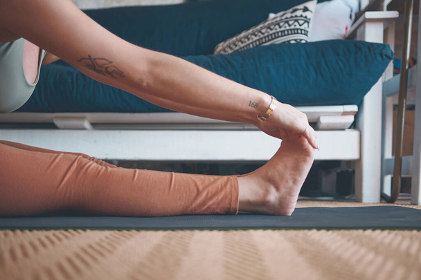 Starting the workout off with some light stretches. Closeup shot of an unrecognisable woman touching her toes while exercising at home - Foto, imagen