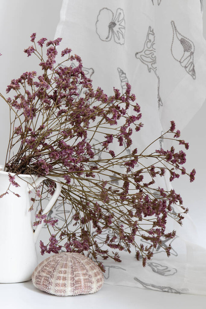 Flor púrpura seca, statice, en un jarrón blanco sobre fondo blanco - Foto, imagen