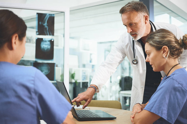 Reunindo seus conhecimentos e habilidades. uma equipe de médicos usando um laptop durante uma reunião em um hospital - Foto, Imagem