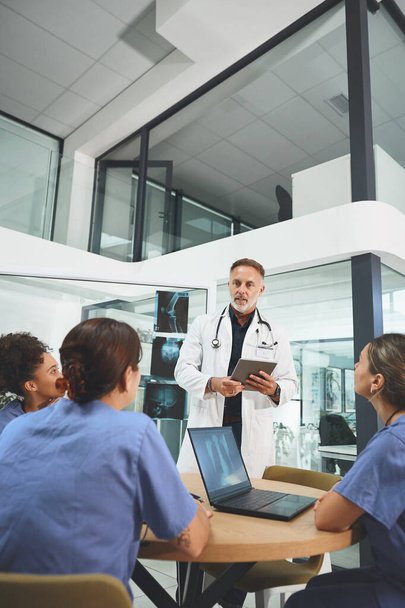 ¿Cómo podemos ayudar mejor al paciente? un médico maduro dirigiendo una discusión con sus colegas en un hospital - Foto, imagen