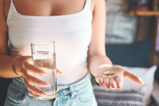 Ne prenez pas de risques, prenez vos vitamines. une femme méconnaissable prenant une pilule avec un verre d'eau à la maison - Photo, image
