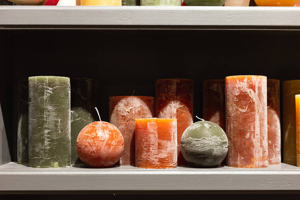 Ζυμαρικά Χρωματιστά πράσινο και πορτοκαλί παραφινούχα κεριά στο ράφι στο κατάστημα κεριών - Φωτογραφία, εικόνα