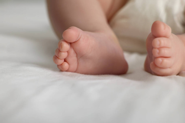 Cute little baby in diaper on bed, closeup - Fotoğraf, Görsel