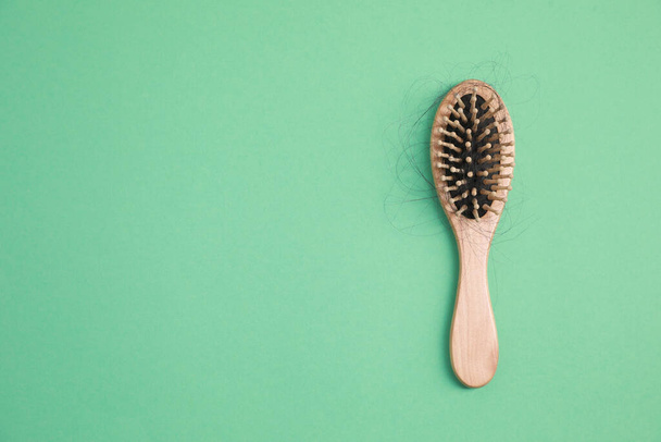 Wooden brush with lost hair on green background, top view. Space for text - Foto, Bild