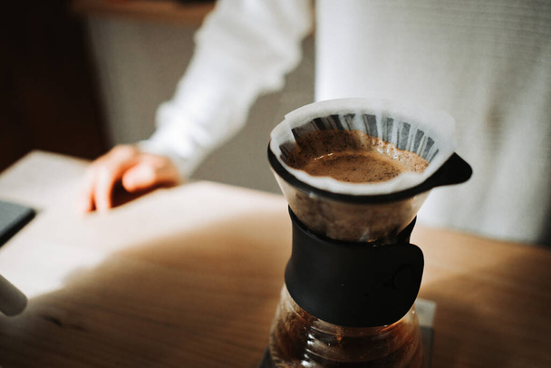 Ein unkenntlich gemachter junger Mann bereitet in einem Café Kaffee mit Chemikalien über Kaffeemaschine und Wasserkocher zu. Hochwertiges Foto - Foto, Bild