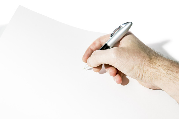 Men's hand writes a pen on a sheet of paper  - Foto, imagen