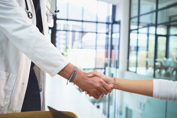 合併は臨床ケアを向上させる。病院での会議中に握手をする医師の閉鎖ショット - 写真・画像