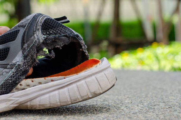 Κοντινό σπασμένο παλιό μαύρο παπούτσι στο πίσω μέρος της φτέρνας. - Φωτογραφία, εικόνα