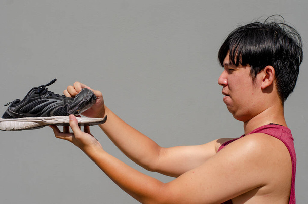 Caucasien asiatique homme tenant de vieilles baskets noires avec en face de chaussure. - Photo, image