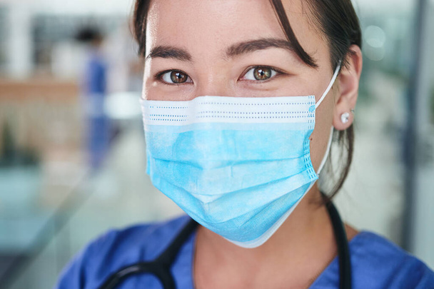 To be a nurse, one must possess natural warmth. Cropped portrait of an attractive young nurse wearing a face mask and standing alone in the clinic - Foto, afbeelding
