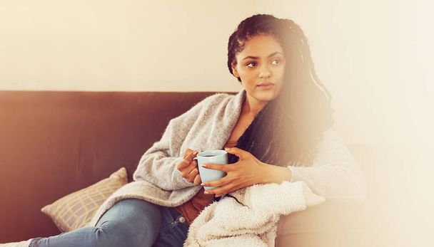 Bere caffè e pensare alle possibilità. una giovane donna che si gode una tazza di caffè nel suo soggiorno - Foto, immagini