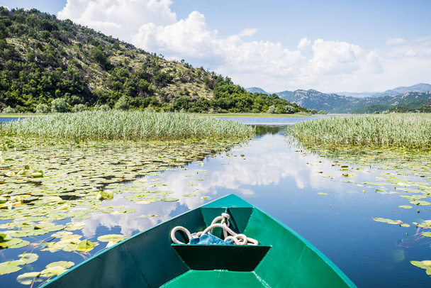Los nenúfares rompen el espejo como reflejos de las nubes y montañas en el río Crnojevica en el lago Skadar en Montenegro. - Foto, Imagen