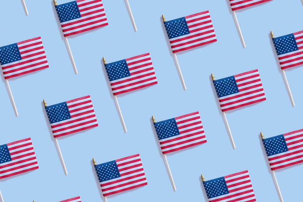 Onafhankelijkheidsdag concept met USA vlaggen patroon bovenaanzicht, plat lag op blauwe achtergrond. - Foto, afbeelding
