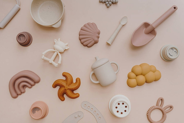 Set of baby kids toys for children. Educational toys in neutral pastel colors. Sand molds, bib, organic teethers, stacking cups on light pink background. Flat lay, top view - 写真・画像