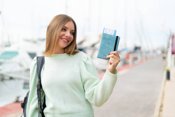 Young pretty blonde woman holding a passport at outdoors with happy expression - Photo, Image