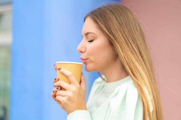 Jeune jolie femme blonde tenant un café à emporter - Photo, image