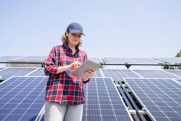 Woman with digital tablet on a background of mobile solar power station. - Foto, imagen