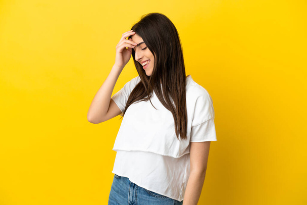 Young caucasian woman isolated on yellow background laughing - 写真・画像