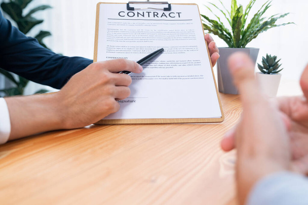 ビジネスマンは企業パートナーシップの契約書を注意深くレビューします。専門的なビジネスの決定のための会議のテーブルの顧客の読書契約の契約および条件。エンティティ - 写真・画像