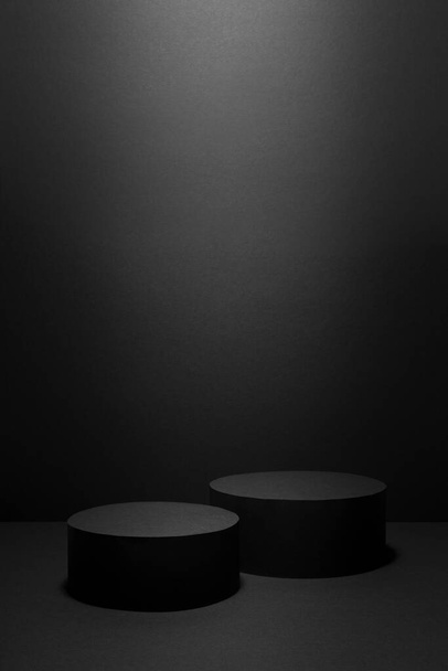 Abstract black stage with two cylinder podiums in light ray with light spot mockup for presentation cosmetic products, goods, advertising, design, showing in trendy exquisite simple style, vertical. - Foto, Imagem