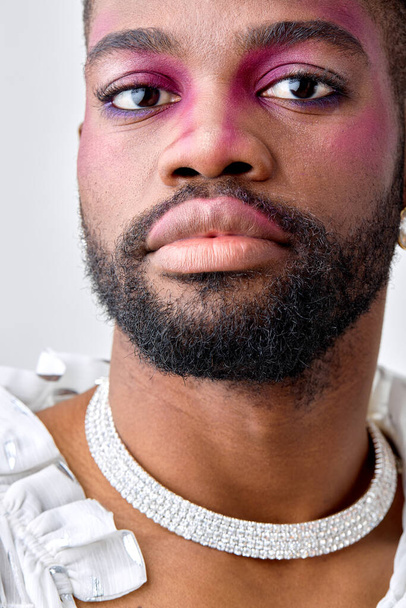 close-up portrait of american androgynous man with pink eyeshadow make-up, look at camera. black american feminine womanlike guy is modern, stylish, self-confident. models, beauty, fashion concept - 写真・画像
