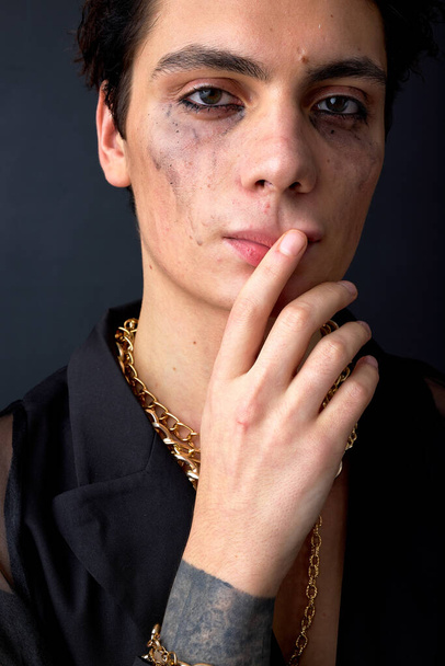 young caucasian upset gay posing with mascara smudged from crying because of discrimination. Concept of diversity, transgender. fashion model isolated over black studio background, portrait - 写真・画像