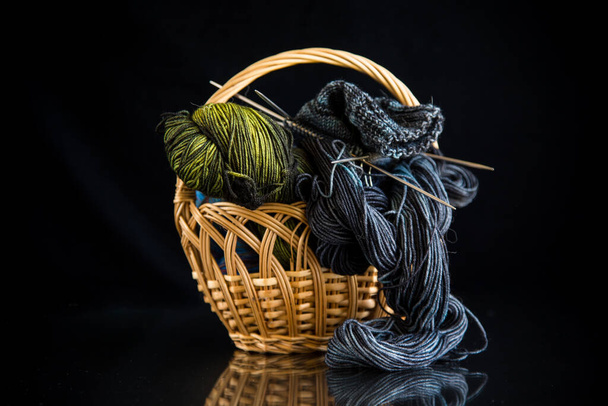 Colored threads, knitting needles and other items for hand knitting, on a black background . - Foto, afbeelding