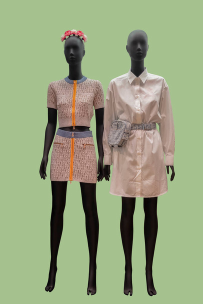 Pełna długość zdjęcia dwóch żeńskich manekinów wystawowych w eleganckich modnych ubraniach odizolowanych na zielonym tle - Zdjęcie, obraz