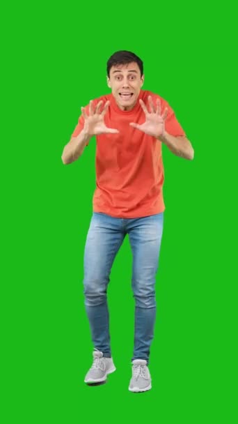 Full body of smiling male in casual clothes pointing and looking at camera isolated on green background in studio - Footage, Video