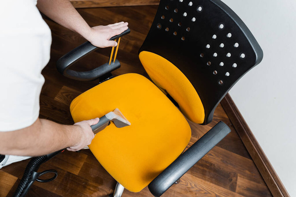 Domestic cleaning service cleaner is removing dirt and dust from chair using dry cleaning machine top view. Line on armchair after dry cleaning with washing vacuum cleaner extractor machine - 写真・画像