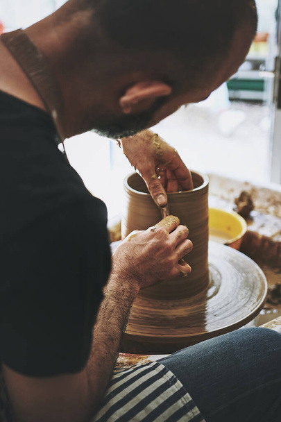 好奇心が創造性の鍵です。陶芸の工房で粘土を扱う無名の男が - 写真・画像
